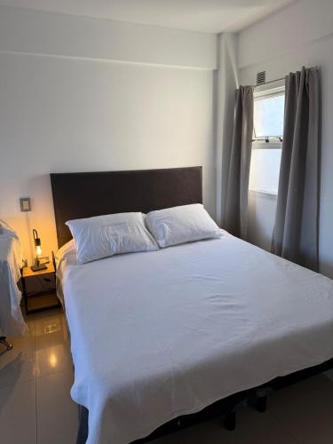 a bedroom with a large white bed with a window at Monoambiente centrico con balcon y pileta in Rosario
