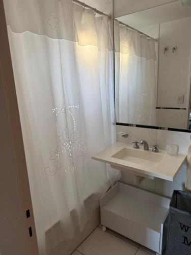 a bathroom with a sink and a white shower curtain at Monoambiente centrico con balcon y pileta in Rosario