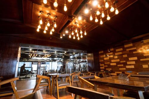 a restaurant with wooden tables and chairs and chandeliers at Central Inn Hotel & Spa in Dhaka