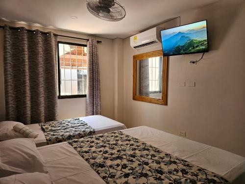 a bedroom with two beds and a flat screen tv at Caribbean Airport Hotel in Cartagena de Indias