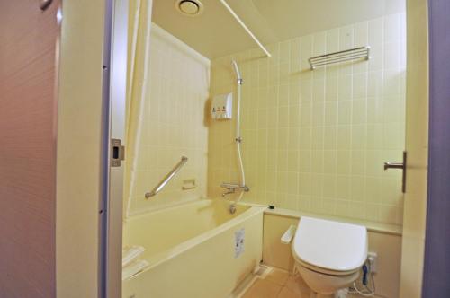 a bathroom with a toilet and a tub and a sink at ホテルベルクラシック北見 in Kitami