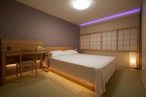 a bedroom with a bed and a desk with a lamp at Sumiyoshi Guesthouse 梦阁 粉浜の宿 in Osaka