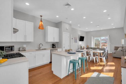a kitchen with white cabinets and a kitchen island with stools at Jennifer's Penthouse Panoramic City Views w Deck in Providence