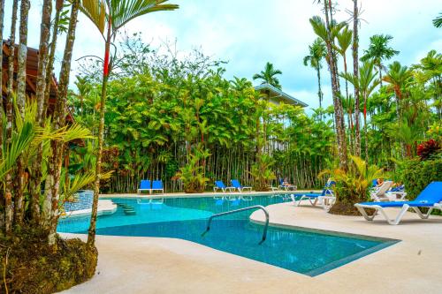 a swimming pool in a resort with palm trees at Arenal Backpackers Resort in Fortuna