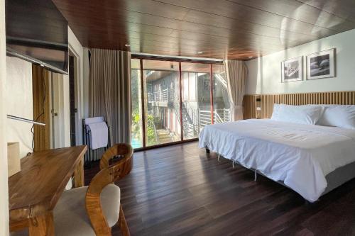 a bedroom with a large white bed and a desk at Novella Tagaytay in Tagaytay