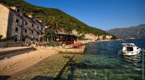 a boat in the water next to a beach at Daria Apartments in Kotor