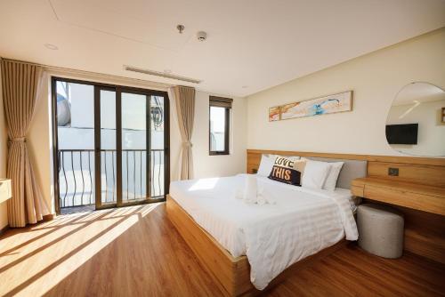 a bedroom with a bed and a large window at Cossy Home by BRIO in Danang