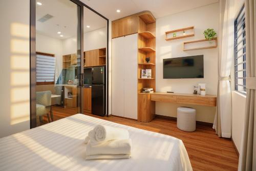 a bedroom with a bed and a kitchen with a tv at Cossy Home by BRIO in Danang