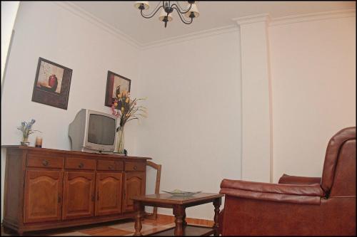 sala de estar con TV y silla en Apartamento Conil San Jose, en Conil de la Frontera