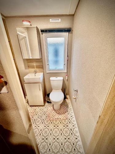 a small bathroom with a toilet and a window at Diamond Touch Home in Saint Osyth