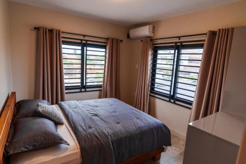 a bedroom with a bed and two windows at Lobby Apartments in Paramaribo