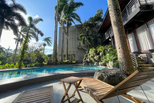 a swimming pool with two chairs and a building at Novella Tagaytay in Tagaytay