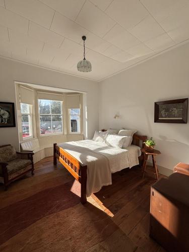 a bedroom with a bed and a chair and a window at Timeless Villa on Parore in Dargaville