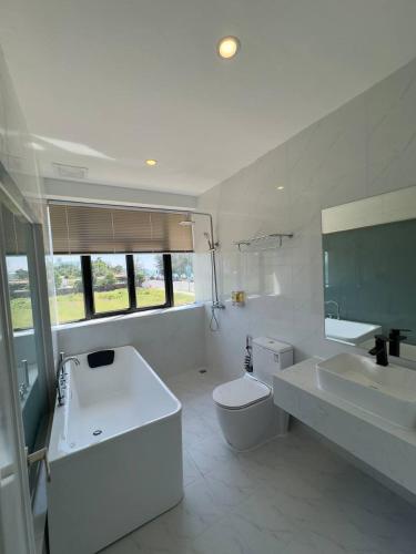 a white bathroom with a tub and a toilet and a sink at Mary Beach Hotel & Resort in Sihanoukville