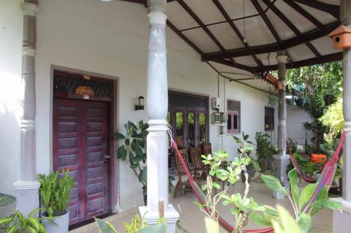 a house with purple doors and a porch with plants at surfing lion villa kudawella in Mawella