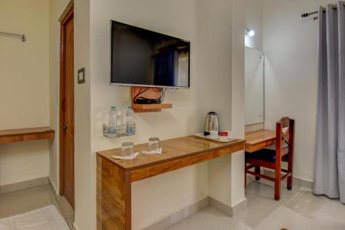 a room with a desk and a tv on the wall at Atithi Comforts in Kushālnagar