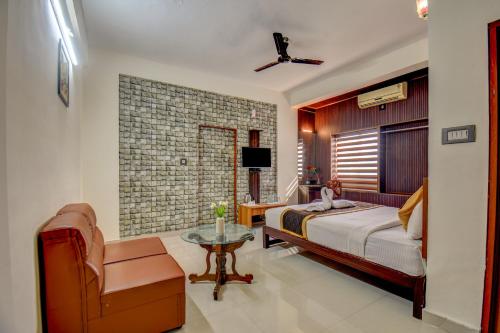 a bedroom with a bed and a chair and a table at Atithi Comforts in Kushālnagar