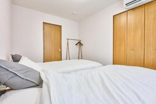 a bedroom with two beds and a wooden cabinet at Furano Noie in Furano