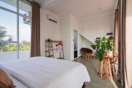a bedroom with a white bed and a large window at Rockvin BnB in Midigama East