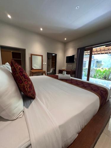a bedroom with a large white bed with a large window at Deswa inn in Ubud