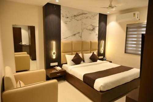 a hotel room with a bed and a chair at Hotel Abhilasha Premium in Dewās