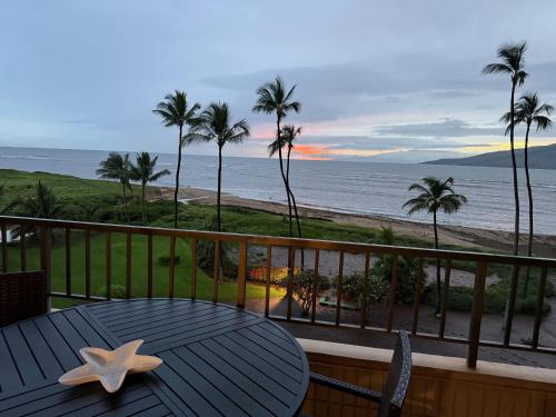 a table on a balcony with a view of the beach at Oceanfront Artist Condo Panoramic Maui Sunsets in Kihei