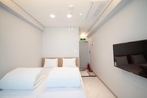 a bedroom with two beds and a flat screen tv at K-Grand Hostel Sinchon in Seoul