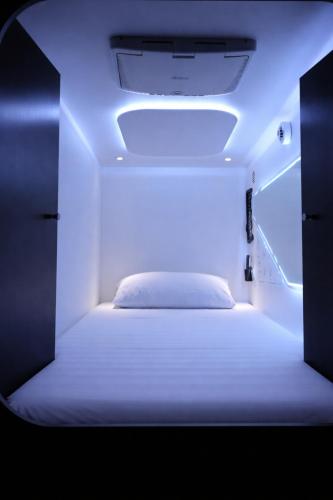 a white bed in a room with a light at Auckland Boutique Capsule in Auckland