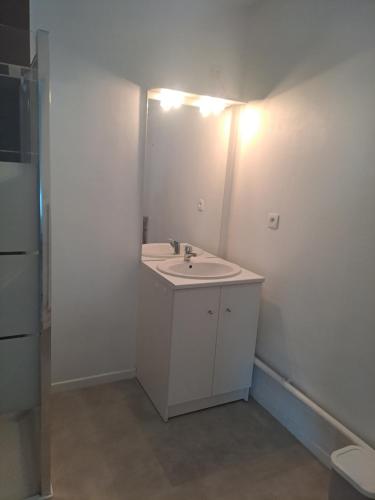 a white bathroom with a sink and a mirror at Gite des Capucines in Bourbourg