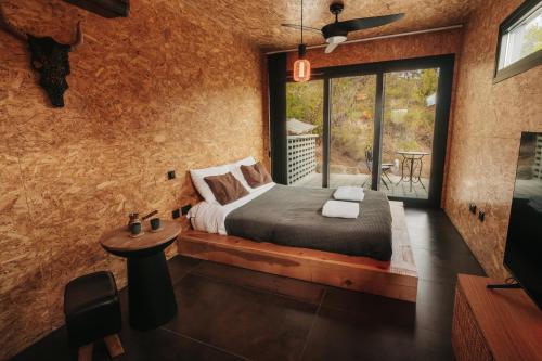 a bedroom with a bed and a large window at Secluded design cabin forest retreat in Cyprus in Kappedhes
