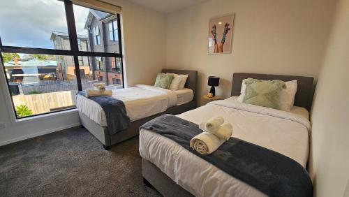 two beds in a room with a window at 20 Te Kanawa Haven in Auckland