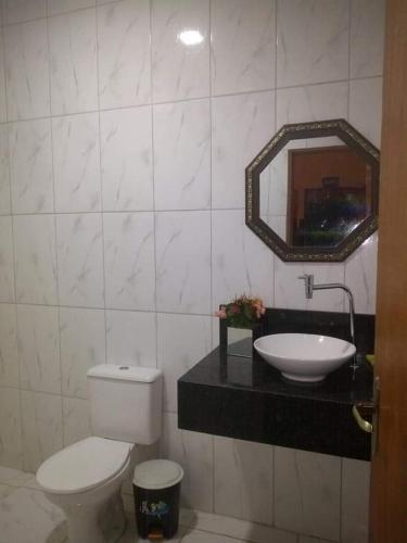 a bathroom with a toilet and a sink and a mirror at Recanto Barretos in Barretos