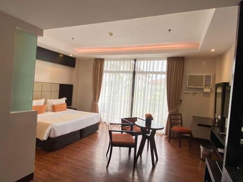 ein Hotelzimmer mit Bett, Tisch und Stühlen in der Unterkunft Hotel Oazis in Butuan