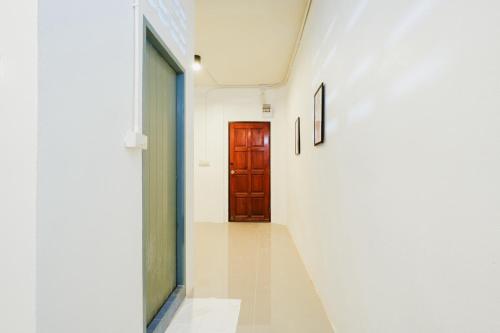 a hallway with a brown door and pictures on the wall at zNAP Ekkamai BTS เอกมัย 42 in Bangkok