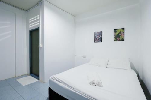 a bedroom with a white bed with two pictures on the wall at zNAP Ekkamai BTS เอกมัย 42 in Bangkok