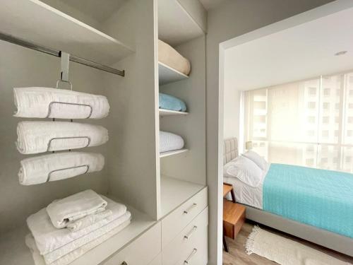 a closet with white towels and a bed at ESPECTACULAR LOFT in Quito