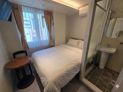 a small room with a bed and a table and a window at D-Haus Hostel Dongdaemun in Seoul