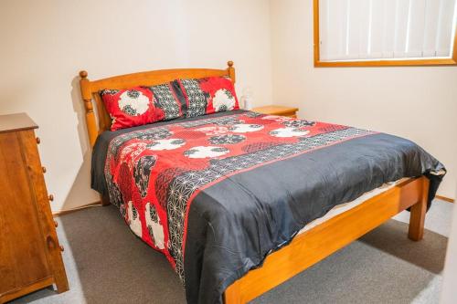 ein Schlafzimmer mit einem Bett mit einer rot-schwarzen Steppdecke in der Unterkunft Conway in Burrum Heads
