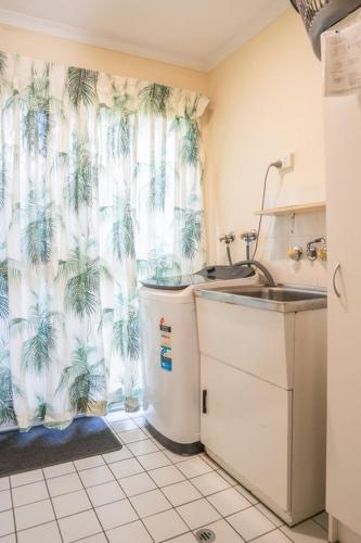 ein Badezimmer mit Waschbecken und Duschvorhang mit Palmen in der Unterkunft Conway in Burrum Heads