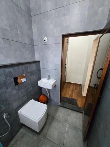 a bathroom with a toilet and a sink and a shower at Dsouza Stay in Mysore