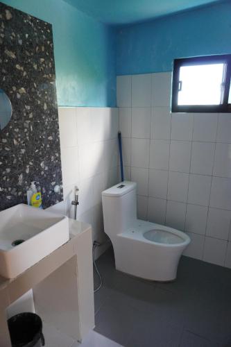 a bathroom with a white toilet and a sink at La Provinzia Exclusive Use - 3 Air-Conditioned Rooms 3 Fan Cooled Huts Good for 12 People in Camotes Islands