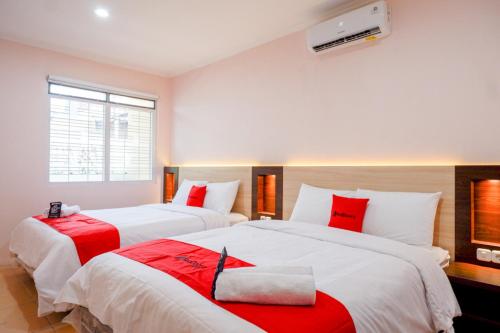 two beds in a room with red and white at RedDoorz near Gejayan 3 in Yogyakarta