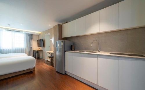 a kitchen with a bed and a refrigerator in a room at Adena Hotel in Busan