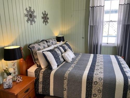 a bedroom with a bed with a blue and white blanket at Marlay Cottage in Stanthorpe
