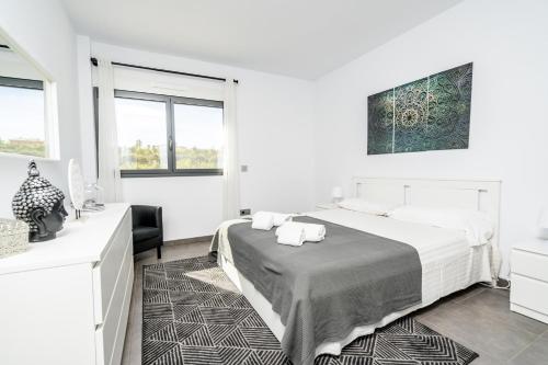 a white bedroom with a bed and two windows at Azahar Sun in Ondara