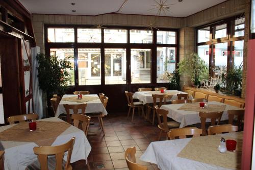 un restaurante con mesas y sillas blancas y ventanas en Gasthof Hausmann en Schlüchtern