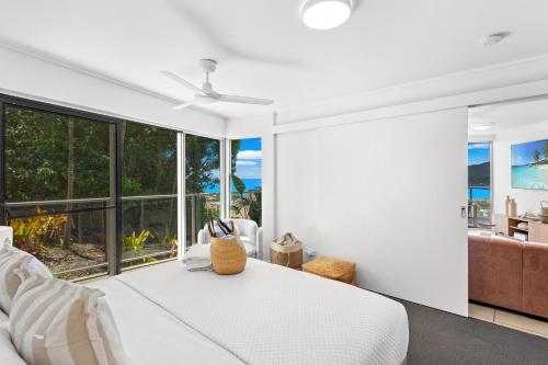 a bedroom with a white bed and large windows at Searene By The Sea in Airlie Beach