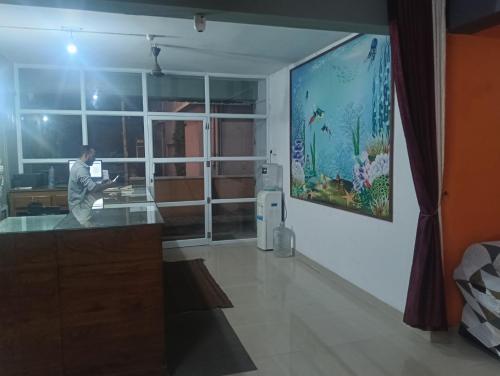 a man standing in a room with a painting on the wall at Safa residency hotel in Perintalmanna
