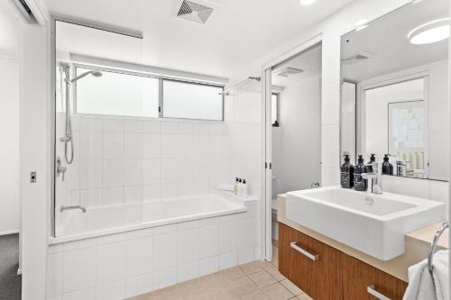 a white bathroom with a tub and a sink at Searene By The Sea in Airlie Beach