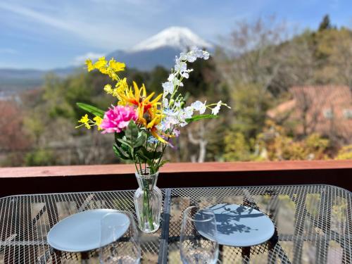 a vase of flowers on a table with a view at りす村別荘 in Yamanakako
